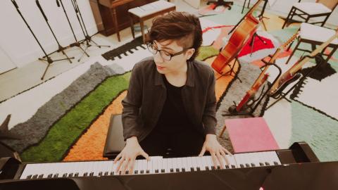 Aerial shot of Carla Patullo playing piano with guitars in the background